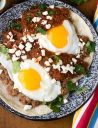 authentic Mexican recipe of Huevos Rancheros on a black speckled plate